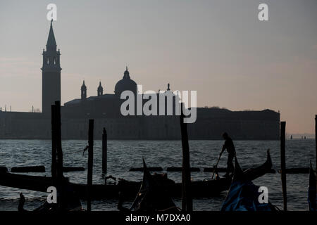 Silhouette d'un gondolier aviron une gondole sur le Grand Canal à Venise, avec l'île de San Giorgio en arrière-plan. Banque D'Images