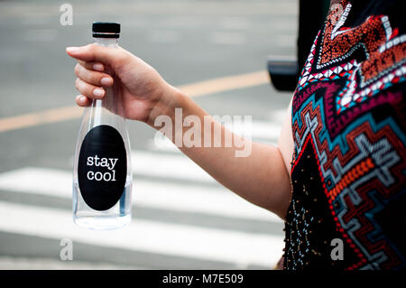 Une femme tient une bouteille platic avec de l'eau piscine avec stay cool message sur elle Banque D'Images