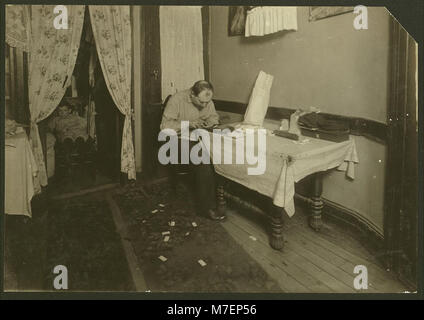 Une photographie montrant des étuis à cigarettes roulant dans un logement, capturant les conditions de vie et les habitudes personnelles dans les espaces urbains à faible revenu au début du XXe siècle. Documenté par E.C. Watson. Banque D'Images