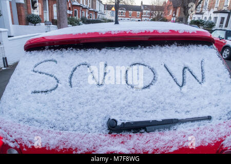 La parole écrite de la neige sur la vitre arrière d'une voiture couverte de neige. Banque D'Images