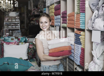 Happy young woman picking client serviettes en ministère du textile Banque D'Images