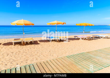 Passerelle en bois et de chaises longues avec parasols sur la belle plage de Praia da Rocha à Portimão, Algarve, Portugal Banque D'Images