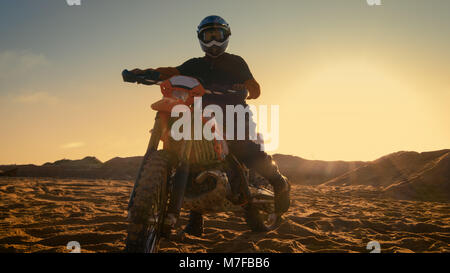 Vue avant tourné du professionnel du pilote de Motocross FMX sa selle de vélo de saleté sur le sable/ Chemin de terre. Banque D'Images