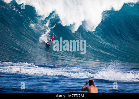 Un œillet de surfer en tombe en bas de la face de Hawaii's big surf à Peahi (Mâchoires) au large de Maui, Hawaii. Banque D'Images