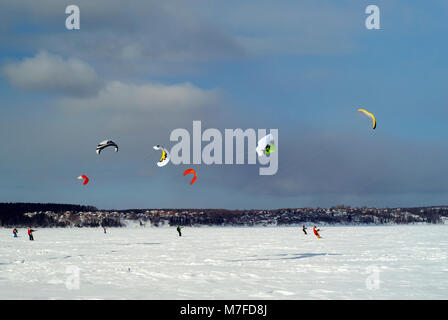 Groupe d'snowkiters glisse sur la glace d'un lac gelé dans un paysage d'hiver Banque D'Images