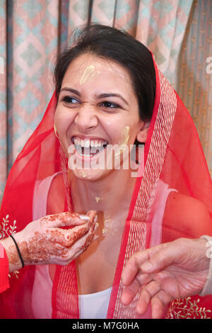 Cérémonie de mariage indien bénédiction avant d'être mariée avec la pâte de curcuma enduite sur le visage par des parents Banque D'Images