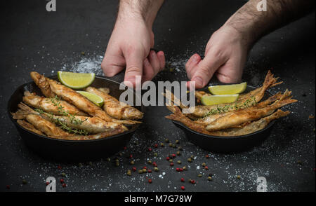 Éperlans frits dans une poêle sur la table avec des épices, de la chaux et le thym. Croustillant de petits poissons. Selective focus Banque D'Images