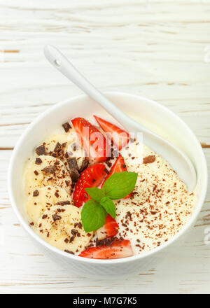 Petit déjeuner santé traditionnels. Yogourt nature avec des fraises, banane et chocolat. Selective focus Banque D'Images