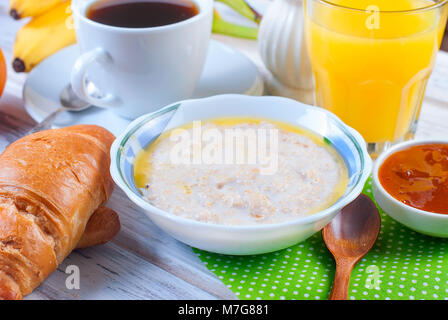 Petit-déjeuner sain avec du gruau avec du beurre, croissant, confiture, café et jus d'orange.. Copier l'espace. Banque D'Images