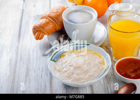 Petit-déjeuner sain avec du gruau avec du beurre, croissant, confiture, café et jus d'orange.. Copier l'espace. Banque D'Images