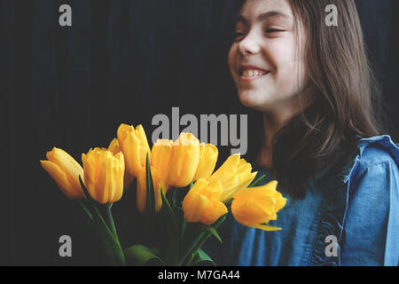 Happy sweet girl avec un bouqet de tulipes jaunes. Banque D'Images