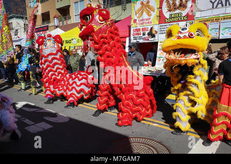 Trois gros Danse avec les Lions à un défilé du Nouvel An chinois font leur chemin passé les spectateurs et des cabines des aliments le long d'une foire de rue. Banque D'Images