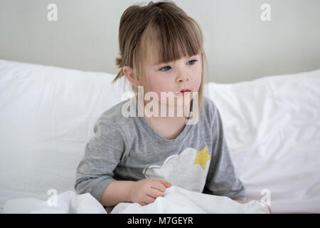 Belle petite fille est assise sur couverture blanche dans l'hôtel Banque D'Images