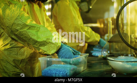 Dans le laboratoire souterrain deux chimistes clandestins de drogues dans les sacs des boîtes. Laboratoire est plein d'équipement illégal. Ils Pack Meth. Banque D'Images