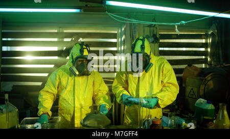 Dans le laboratoire souterrain deux chimistes clandestins de drogues dans les sacs des boîtes. Laboratoire est plein de verrerie et d'autres produits stupéfiants. Banque D'Images