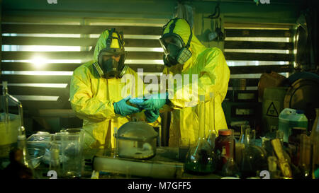 Dans le laboratoire souterrain deux chimistes clandestins de drogues dans les sacs des boîtes. Laboratoire est plein de verrerie et d'autres produits stupéfiants Banque D'Images