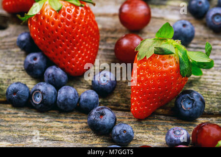 Les bleuets Fraises Raisins fruits sur la plaque en bois sur fond de bois produits sains biologiques Banque D'Images