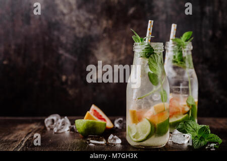 Deux bouteilles en verre rempli d'eau froide d'agrumes sur fond sombre. Banque D'Images