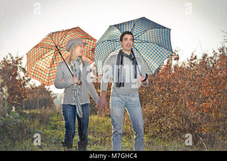 Jeune couple sous un parasol sur la pluie d'automne Banque D'Images