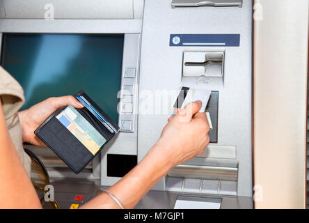 Retrait d'espèces. Woman's hand inserting Visa carte plastique dans le distributeur Banque D'Images