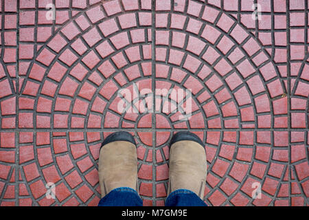 Chaussures en daim marron debout sur un sol rouge de décider quoi faire ensuite. Banque D'Images