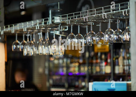 Verres de vin accrocher sur le bar avec table fond blured Banque D'Images