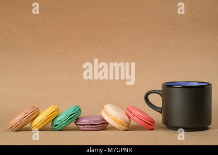 Macarons de couleur noir et marron sur la tasse de café du papier craft arrière-plan. Vue de côté avec copie espace Banque D'Images