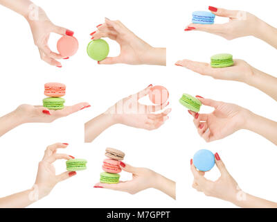 Femme les mains avec une belle peau et la tenue du vernis à ongles, de montrer ou de mesurer les macarons. Isolé sur blanc, chemin de détourage inclus Banque D'Images