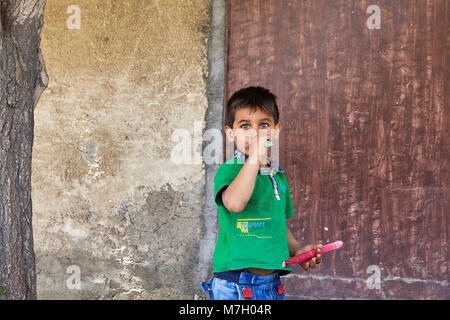 Kashan, Iran - le 26 avril 2017 : un petit garçon inconnu, environ 5 ans, suce une sucette près du mur de la chambre. Banque D'Images