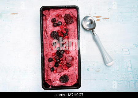 Vue de dessus de sorbet fruits rouges avec scoop sur fond en bois bleu. Banque D'Images