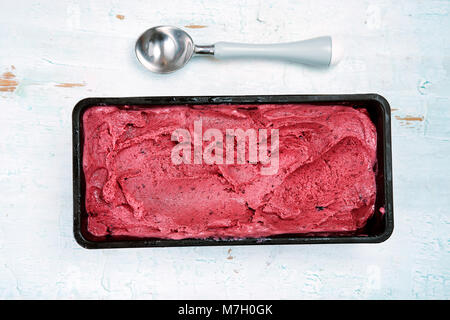 Vue de dessus de sorbet fruits rouges avec scoop sur fond en bois bleu. Banque D'Images