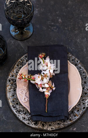 Réglage de la table de printemps en noir, gris et rose avec des amandes en fleurs et la direction générale de l'espace négatif. Banque D'Images