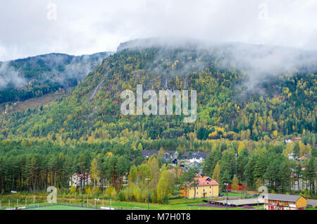 Vue à longue distance d'Evje cityline dominé par des montagnes de basse couverte par la forêt et les nuages, le centre de la Norvège, de l'Europe. Banque D'Images