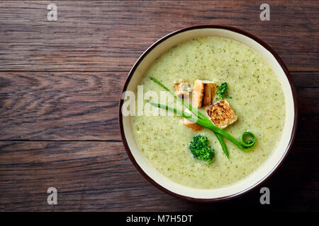 Vegaterian aux pois cassés d'hiver soupe de curcuma décoré de croûtons et de verdure en violet foncé Bol en céramique sur fond de bois, vue du dessus, close-up. T Banque D'Images