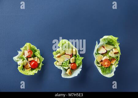 Yummy Vue de dessus la composition de produits frais salade saine artistiquement servi sur des feuilles de laitue sur fond sombre. Salade César traditionnelle avec de la laitue, cro Banque D'Images