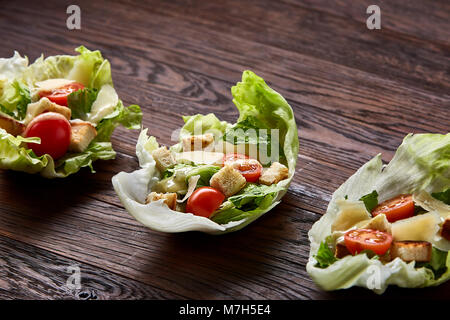 Yummy Vue de dessus la composition de produits frais salade saine artistiquement servi sur des feuilles de laitue sur vintage table en bois. César traditionnelle salade de laitue Banque D'Images