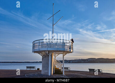 Une femme regardant le coucher de soleil sur l'estuaire de la Tay à partir d'une plate-forme d'observation circulaire à Broughty Ferry Harbour , près de Dundee en Ecosse. Banque D'Images