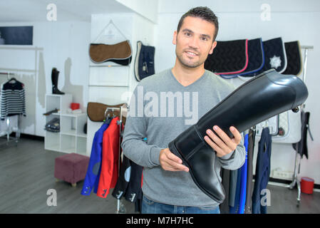 L'homme à equestrian store holding bottes d'équitation Banque D'Images