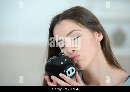 Young woman kissing piggy bank Banque D'Images