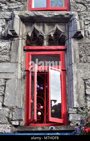 Cadre en bois peint rouge vintage à la place de la fenêtre ancienne fenêtre en arche sur l'historique bâtiment en pierre. Banque D'Images