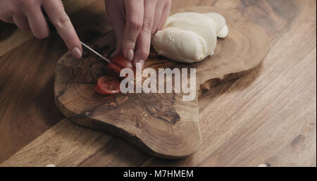 Les jeunes femmes en tranches de tomate cerise sur planche de bois, wode photo Banque D'Images