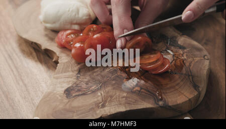 Les jeunes femmes en tranches de tomate cerise sur planche de bois, wode photo Banque D'Images