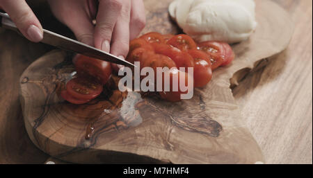 Les jeunes femmes en tranches de tomate cerise sur planche de bois, wode photo Banque D'Images