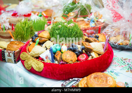 La plaque avec la pâte à bonbons célébration Novruz en Azerbaïdjan, shecurbura avec pakhlava et l'agropyre semeni vert frais et de fleurs Banque D'Images