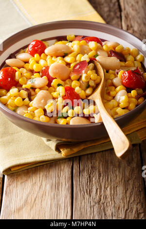 Accueil succotash de haricots, tomates, poivrons et lardons close up dans un bol sur la table verticale. Banque D'Images