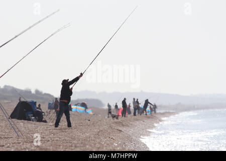Les pêcheurs à la ligne dans une brume de chaleur sur une chaude journée sur la plage de Chesil UK, principalement la pêche du maquereau Banque D'Images