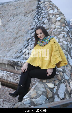 Jolie fille dans un poncho Tricoté au crochet jaune, souriant et gai Banque D'Images