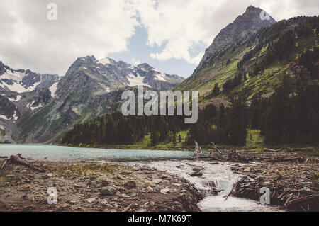 La fonte des glaciers dans les montagnes. L'eau s'écoule du lac formant une rivière. Banque D'Images