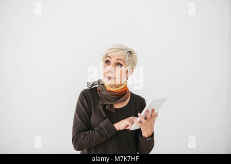 Une vieille femme moderne est titulaire d'un comprimé dans ses mains et l'utilise. L'ancienne génération et la technologie moderne. Banque D'Images