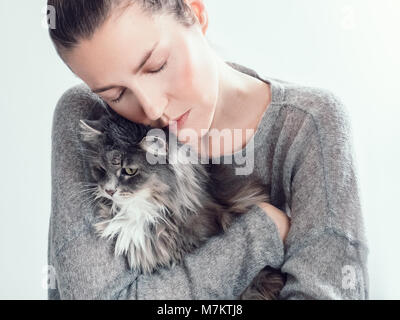 Jeune femme élégante, serrant doucement son chaton sur un fond blanc. Les gens, les animaux, les soins Banque D'Images